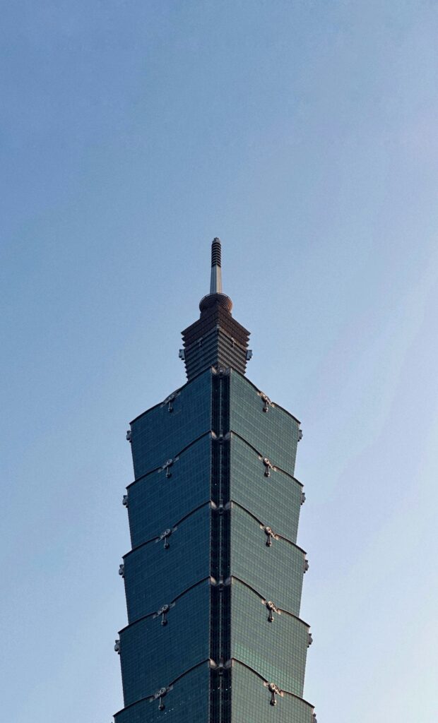 Top of Taipei 101 skyscraper with its spire reaching into a clear blue sky