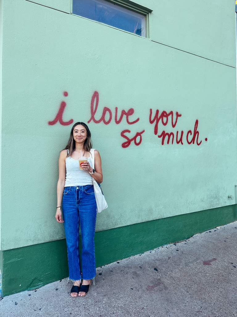 a travel blogger in front of the i love you so much mural in austin texas, spending one day in austin texas