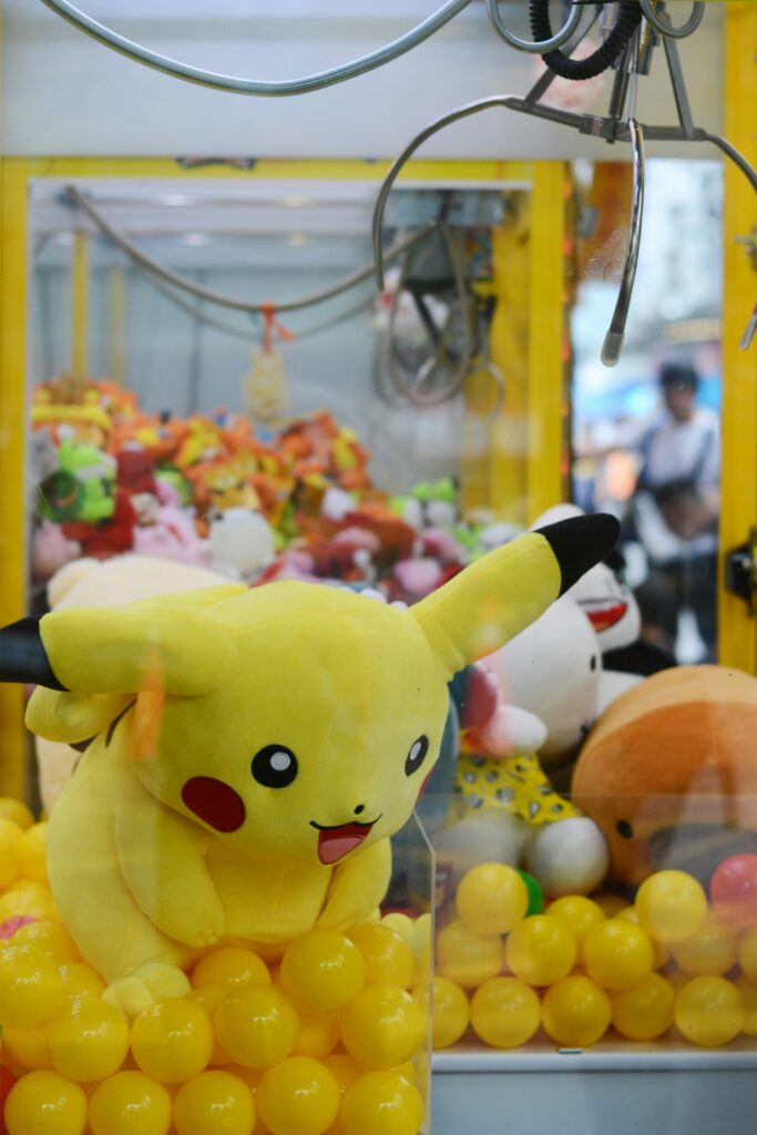 Yellow Pikachu plush in a claw machine among a mound of yellow balls, arcade prize scene.