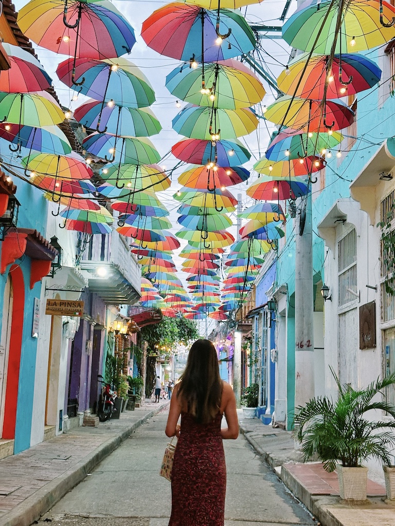 girl standing under beautiful rainbow umbrellas in getsemani neighborhood in cartagena colombia